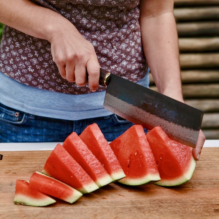 Frau schneidet Melone mit asiatischem Messer